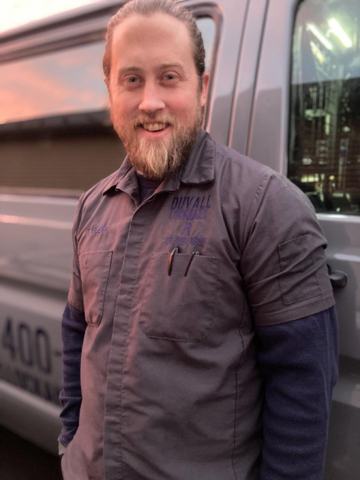 Tyler Duvall in a Duvall Lock and Key work shirt, standing by the van